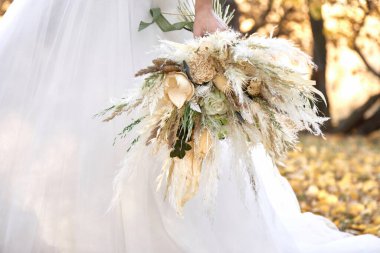Gelinin elleri güzel bir sonbahar buketi tutuyor.