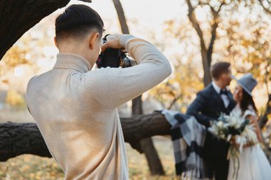 Profesyonel düğün fotoğrafçısı sonbaharda gelin ve damadın fotoğraflarını çekiyor.