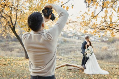 Profesyonel düğün fotoğrafçısı iş başında. Sonbaharda gelin ve damat doğada