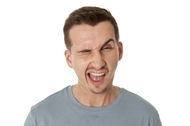 Genç mutlu bir adamın beyaz arka plandaki kameraya göz kırpan portresi.