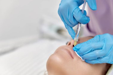 Güzellik uzmanı güzel bir kadının dudaklarını büyütmek için iğne yapar. Prosedür dudak büyütme