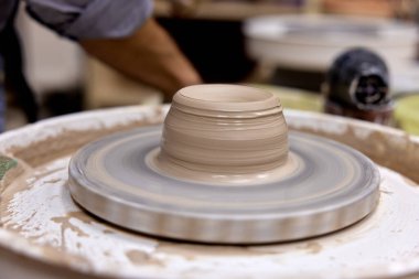 Erkek elleri çanak çömlek çarkında seramik bardak yapıyor.