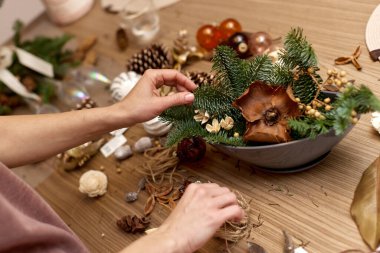 Kadın köknar dallarıyla Noel düzenlemesi yapıyor. el yapımı dekor.