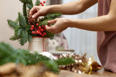 Kadın köknar dallarıyla Noel düzenlemesi yapıyor. el yapımı dekor.