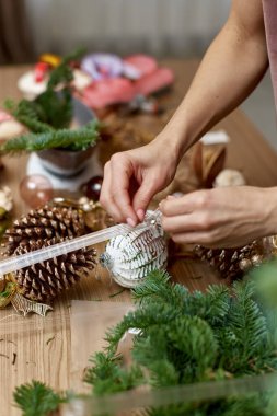 Kadın köknar dallarıyla Noel düzenlemesi yapıyor. el yapımı dekor.