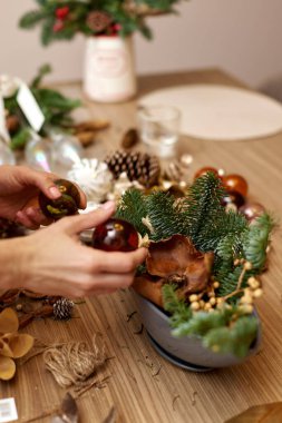 Kadın elleri köknar dalları ve kurumuş çiçeklerle el yapımı Noel sanatları dekoru yaratıyor.