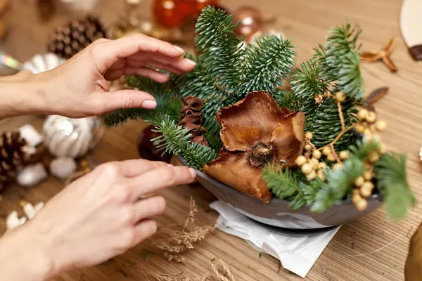 Kadın elleri köknar dallarıyla el yapımı Noel zanaatı yaratıyor..