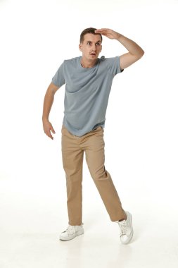 Uzaktan bakan genç bir adam, beyaz arka planda eli kolu bağlı.