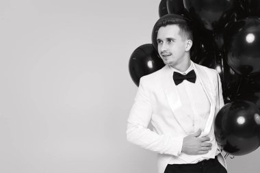 Siyah balonlu beyaz takım elbiseli şık bir adam. kopyalama alanı. bayram kutlaması