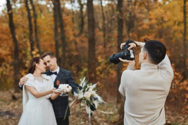 Düğün fotoğrafçısı sonbaharda gelin ve damadın fotoğraflarını çekiyor.