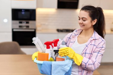 Lastik koruyucu sarı eldivenli bir kadın temizlik malzemesi tutuyor. ev işleri.