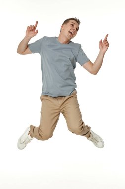 Genç adam gülümsüyor, beyaz arka planda yüksekten atlıyor.