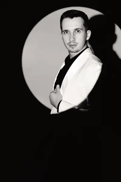 elegant man in white suit tuxedo in the circle of light, black and white
