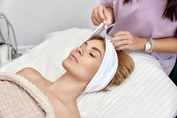 Kosmetolog Nakładający Biały Ręcznik Głowę Pacjentki Salonie Piękności — Zdjęcie stockowe