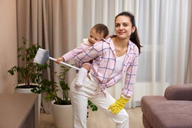 Mutlu anne ev hanımı kucağında tatlı bir kız çocuğu, evde ev işi yapıyor, mutlu aile eğleniyor.