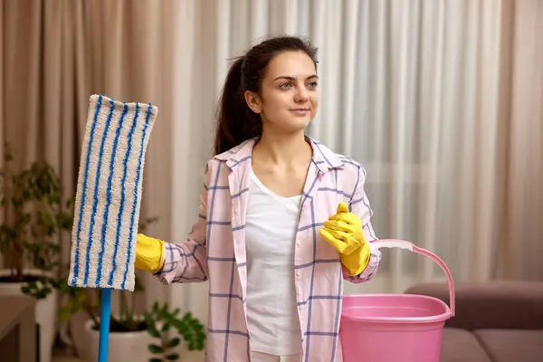 woman cleaning floor at living room, girl holding bucket and mop, daily housekeeping