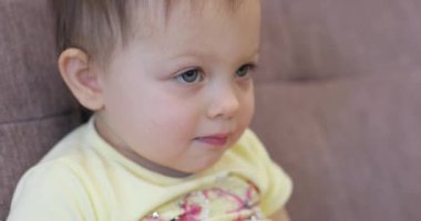 Küçük bebek evde oturmuş televizyon seyrediyor.