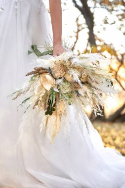 Gelinin elleri güzel bir sonbahar buketi tutuyor.