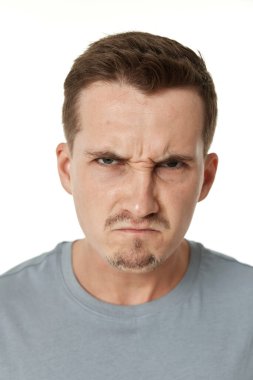 Beyaz stüdyo arka planında duran sinirli adam.