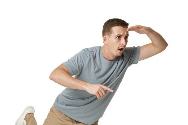 Uzaktan bakan genç bir adam, beyaz arka planda eli kolu bağlı.