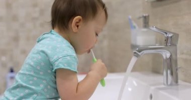 Banyoda diş fırçasıyla dişlerini fırçalayan küçük bir kız çocuğu.