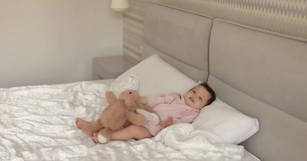 かわいい小さな子供はベッドでおもちゃのバニーと遊んでいます — ストック動画