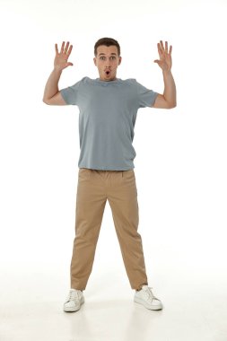 Beyaz stüdyo arka planında kameraya bakan şaşırmış bir adam.