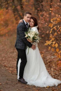 Beyaz gelinlik içinde güzel gelin ve damat kırsalda dikiliyor.