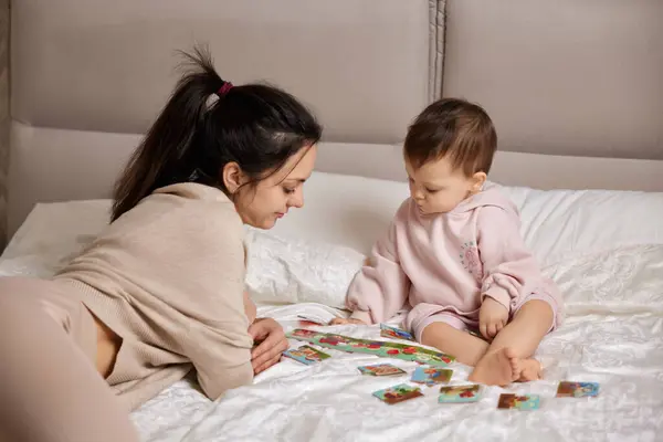 美丽的母亲在卧室里和小女孩玩拼图游戏 — 图库照片