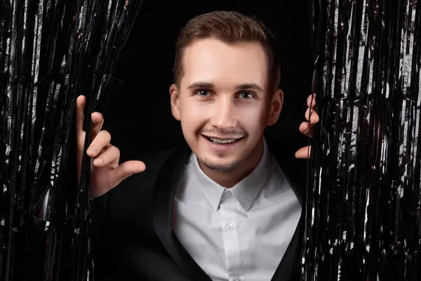 stock image Happy handsome man in black jacket smiling on glitter background.