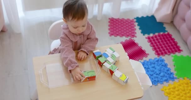 彼女の部屋のテーブルの上のブロックで遊んでいる幸せなかわいい子供の赤ん坊の女の子 — ストック動画