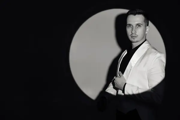 elegant man in white suit tuxedo in the circle of light, copy space. black and white