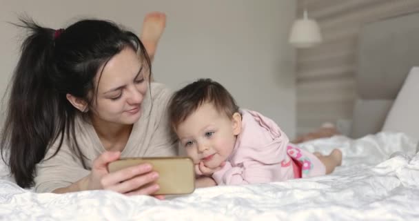 Moeder Schattig Klein Kind Spelen Met Smartphone Terwijl Zitten Bed — Stockvideo