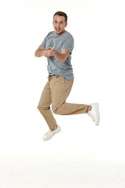 Mutlu adam beyaz stüdyo arka planındaki kameraya bakıyor.