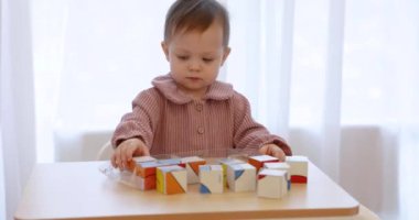 Küçük, mutlu bir kız bebek. Odasındaki küplerle oynuyor.