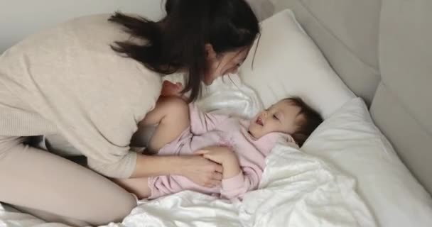 Молодая Мама Щекочет Свою Веселую Смеющуюся Маленькую Дочку Утренней Спальне — стоковое видео