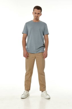 Beyaz stüdyo arka planında duran sinirli adam.