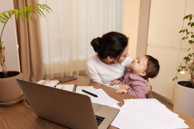 Mutlu bir kadın çalışıyor ve küçük kızıyla evde oynuyor.