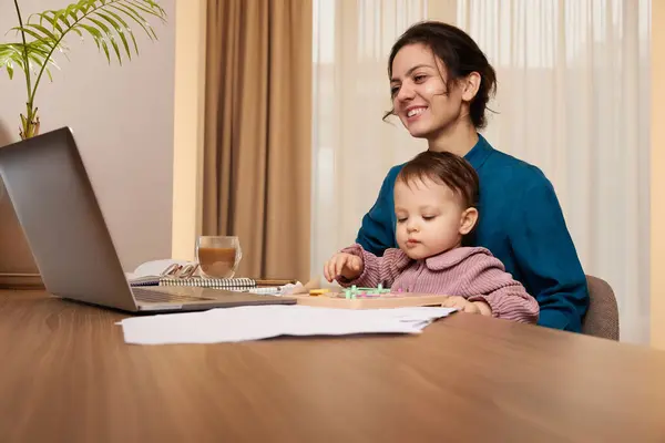 自宅で彼女の小さな子供の女の子とラップトップに取り組んでいる幸せな美しいビジネスマン — ストック写真