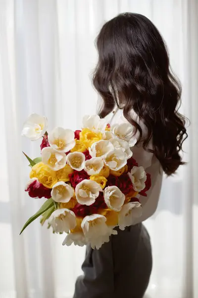 Gyönyörű Göndör Tavaszi Virágokkal Tulipán Kezében Nézi Ablakot Nőnap Jogdíjmentes Stock Fotók