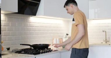 Kafkas adam kahvaltı için omlet hazırlıyor ve modern iç mutfakta dans ediyor.