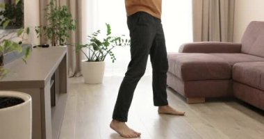 Siyah pantolonlu erkek bacakları evde yerde dans ediyor..