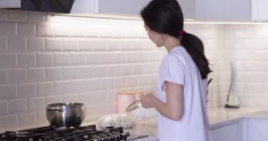 Kadın mutfakta kaynar suda hamur köftesi pişiriyor.