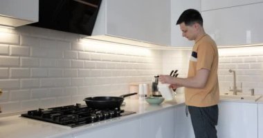 Kafkas adam, modern iç mutfakta kahvaltıya omlet hazırlıyor.