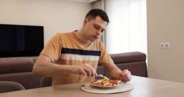 Beyaz bir adam mutfakta kahvaltı yapıyor.