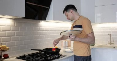 Kafkas adam, modern iç mutfakta kahvaltıya omlet hazırlıyor.