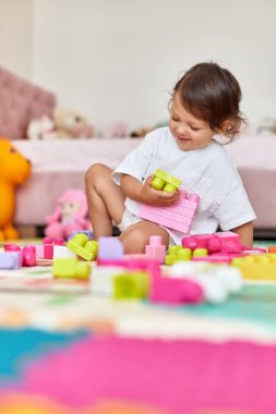 Sevimli bebek odasında renkli oyuncak bloklarıyla oynuyor.