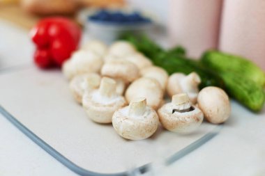 Beyaz bir mutfakta kesim tahtasında çiğ şampiyon.