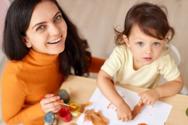 Mutlu küçük kız ve annesi sonbahar tatili için çizim yapıyorlar. Mutlu aile tabloları Sonbahar yaprakları