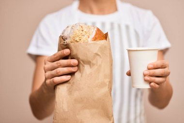 Önlüklü kadın müşteriye bir fincan kahve ve taze kruvasan servis ediyor.